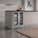 Stainless steel dual-zone beverage refrigerator integrated into a modern kitchen island with flat-panel gray cabinets.