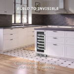 Under-counter built-in wine cooler fitted with a custom white panel and handle to match adjacent white kitchen island cabinetry, titled "BUILD TO INVISIBLE: Custom Panel and Handle Match Your Cabinetry.