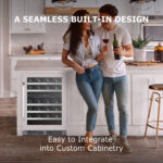 A smiling couple holding wine in a contemporary kitchen with an under-counter wine cooler seamlessly installed into the white kitchen island.